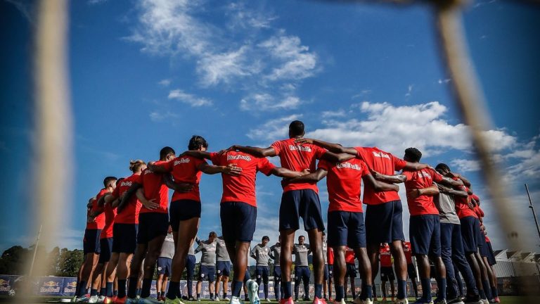 Jogadores do Bragantino estão reunidos e abraçados no centro do gramado