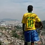 Menino com a camisa 10 da Seleção Brasileira segura uma bola de futebol